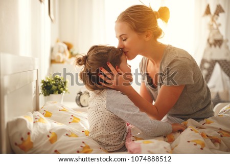 morning awakening. mother wakes her daughter in bed in morning
