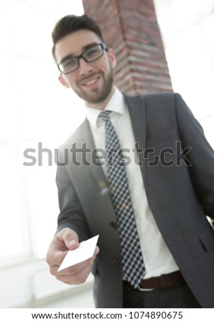 Businessman giving a card. Close-up photo in loft office