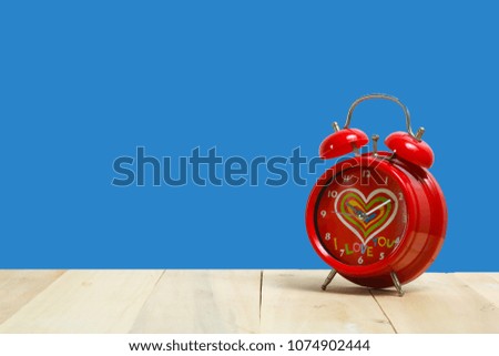 Red alarm clock on old wood with blue background