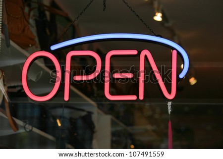 A red and blue open sign in the window of a store