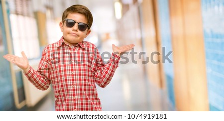 Handsome toddler child with green eyes doubt expression, confuse and wonder concept, uncertain future at school corridor
