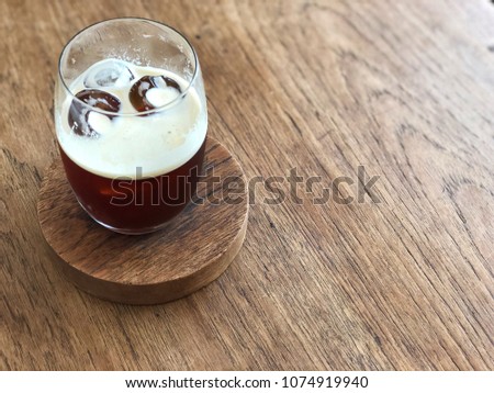 Nitro cold brew coffee glass on the wooden table with natural light and copy space.