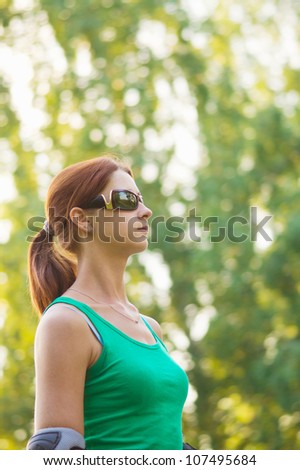 Sporty girl in sunglasses rollerskating in park
