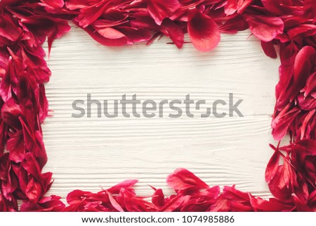 lovely red peonies petals frame on rustic white wooden background, top view, space for text. floral greeting card mock-up, flat lay. happy mothers day or valentines concept.