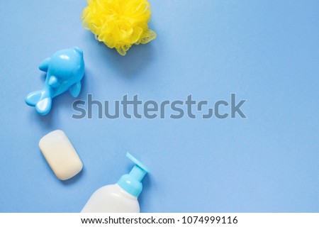 Yellow sponge, blue plastic toy dolphin and liquid soap. Flat lay baby bath products. Mockup