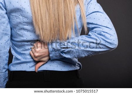 Close-up of back view of business lady showing thumb down gesture on black background