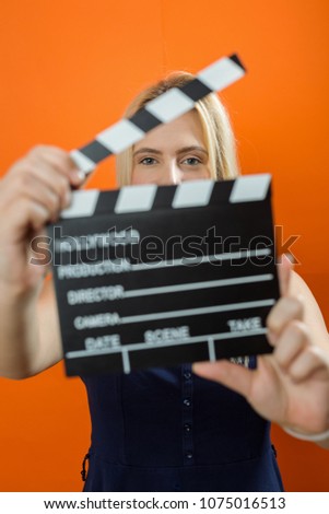 Woman holding an movie clapper in studio
