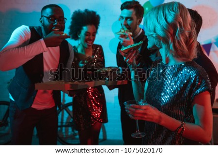 Partying diverse people eating pizza and holding drinks
