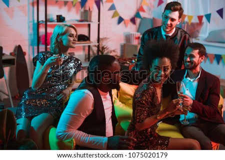 Multiracial smiling friends having party with drinks in decorated room