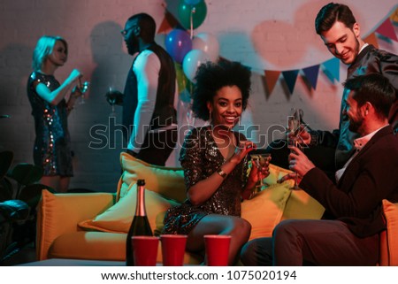 Multiracial friends having party with drinks in decorated room