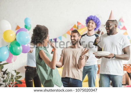 Young joyful male and female friends celebrating birthday with cake