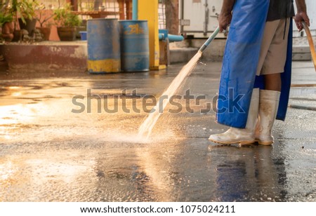 worker splash water for cleaning the factory floor.