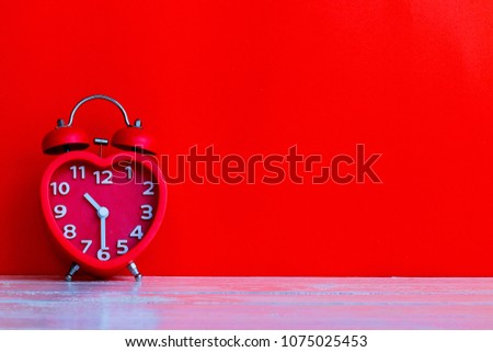 Close up red alarm clock mark at 10.30 o'clock with red space background put on wooden table top
