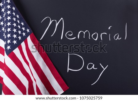 "Memorial Day" written on a blackboard next to the American flag
