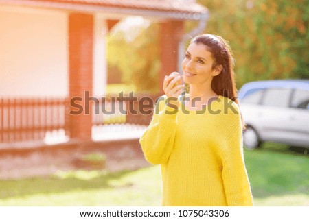 A beautiful woman eating a Apple in the Garden in Autumn.
