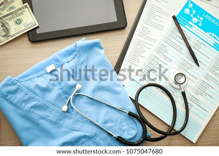 Stethoscope with blue doctor's uniform and laboratory tests on table