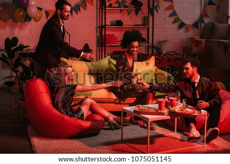 Young people celebrating with drinks in cozy room