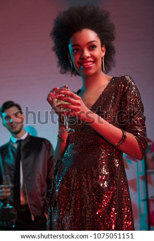 African american woman holding glass with cocktail by man at party