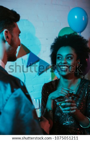 Happy couple holding glasses and talking at party