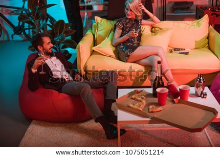 Glamorous man and woman holding glasses and relaxing at party