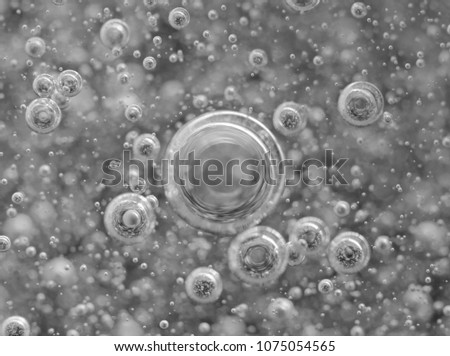 Black-and-white background with big and small grey bubbles inside a gray liquid. 