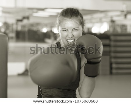 Portrait of young woman in red boxing gloves training in gym