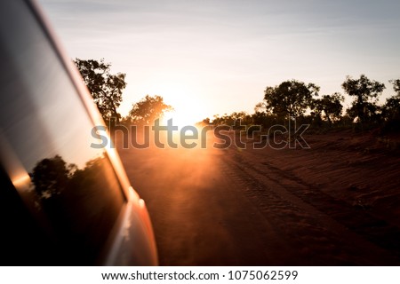 Looking back at the sunset from a moving car on a dusty road in outback Western Australia near Broome.