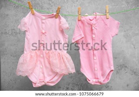 Baby clothes hanging on washing line against gray background