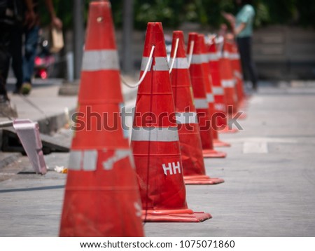 Orange traffic cones lined up to protect road users from harm. And prevent unrelated people from entering the workplace. By the traffic cones, the longitudinal road from the repair point to the end.