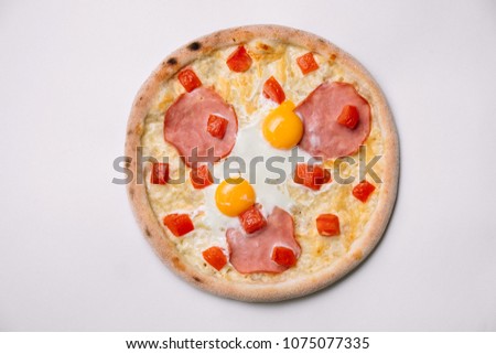 Breakfast pizza with fried eggs and ham isolated on white. Top view