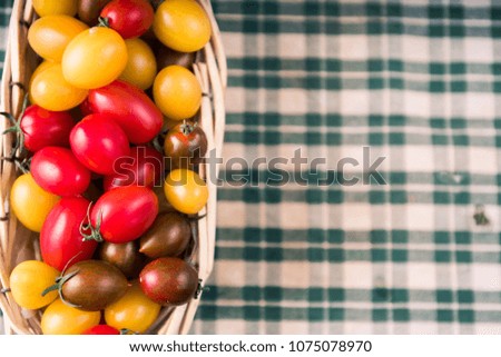 Freshly colored mixed  cherry tomatoes
inside a wooden container ,top view, over a rustic background