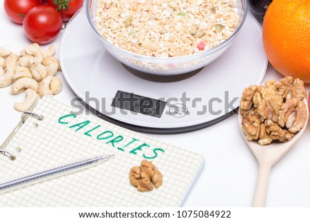 Weighing products, vegetables, fruits on kitchen electronic scales and writing values to the list for calorie counting and making up a proper diet menu, dieting Royalty-Free Stock Photo #1075084922