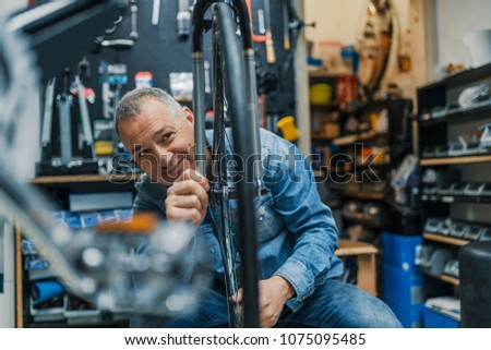 Bicycle mechanic carrying a bike in workshop. Repairman repairing bicycle in workshop. 