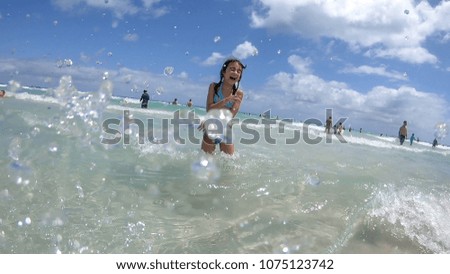 Young girl and ocean splashes on a beautiful day.