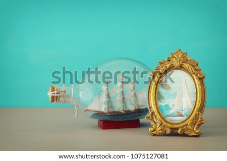 nautical concept image with sail boat in the bottle over wooden table. Selective focus
