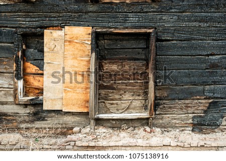 Charred black wooden wall with window. Front View of a burned boards of slum house 