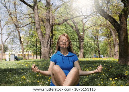 Relaxed woman meditating in Lotus position during sunny day.