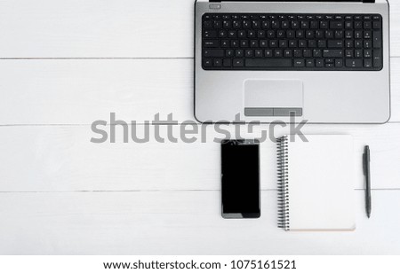 Top view on white wooden table open laptop computer, empty notebook and mobile smartphone with blank screen, copy space. Flat lay