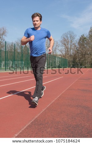 Adult male athlete running on outdoor sports field