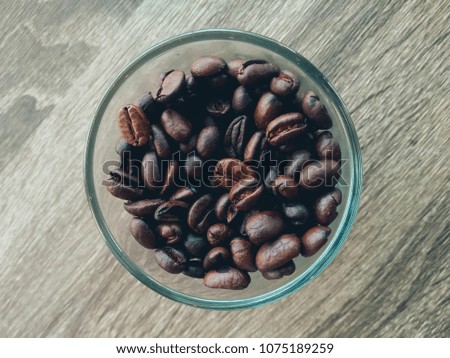 a glass of coffee bean on wood table background.