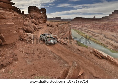 A lifted truck delicately makes it's way along a cliff in Utah Royalty-Free Stock Photo #1075196714