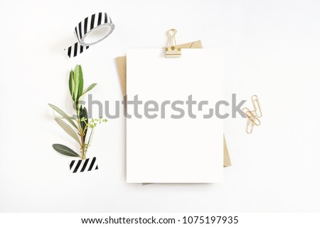 Feminine stationery,  desktop mock-up scene. Blank greeting card, craft envelope, washi tape and golden paper, binder clips with olive branch.White table background. Flat lay, top view.  Royalty-Free Stock Photo #1075197935