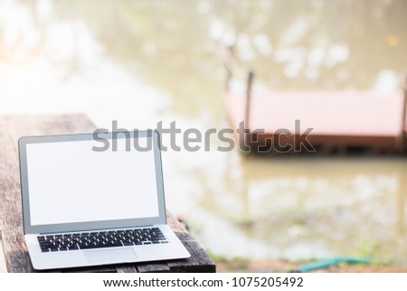Blank screen laptop on wood blurred river nature background.