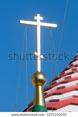 The golden cross on the Orthodox Temple against the blue sky