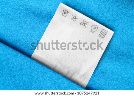 Care clothes label on blue textile background closeup