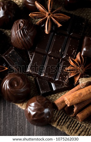 Assortment of dark, white and milk chocolate stack, chips. Chocolate and coffee beans on rustic wooden sacking background. Spices, cinnamon. Selective macro focus. Chocolates background. Sweets