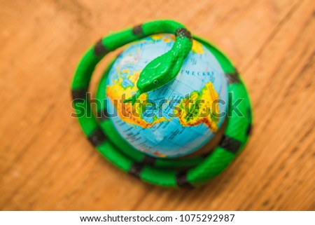 big green poisonous snake arond globe map