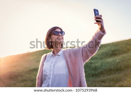 Beautiful girl outdoors using phone and taking selfie 