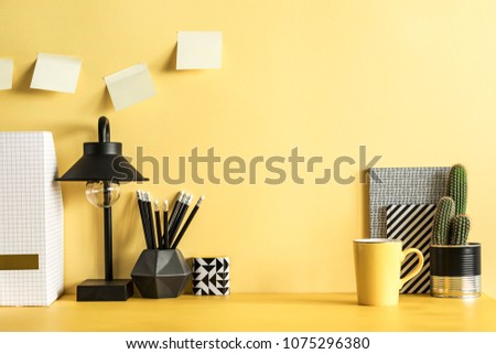 Yellow desk with cacti, office accessories, sticky notes and lamp. Creative workspace with yellow background.