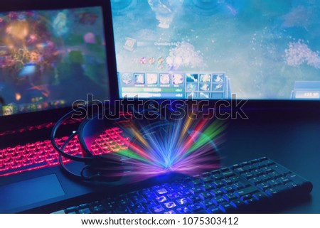 Laptop, computer, keyboard, mouse, headphones accessories for the gamer on the background of the monitor with the game, the workflow